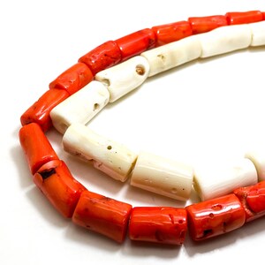May include: A strand of red and white coral beads. The beads are cylindrical and have a rough, natural texture.