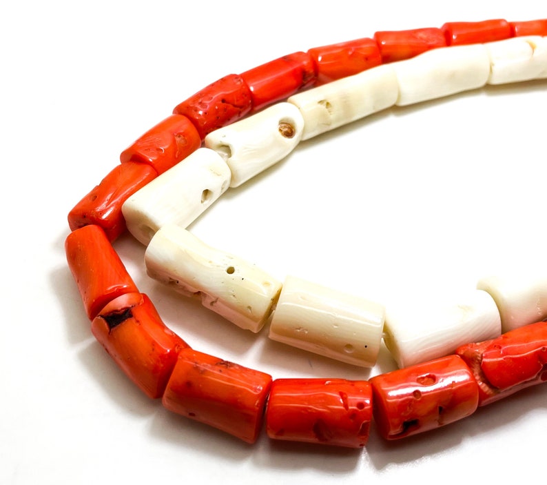 May include: A strand of red and white coral beads. The beads are cylindrical and have a rough, natural texture.