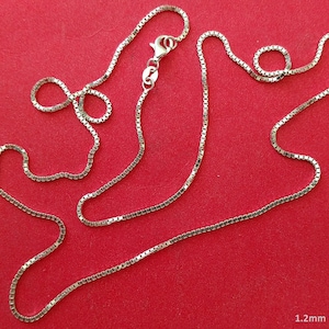 May include: A silver chain necklace with a box chain design. The chain is 1.2 mm wide.