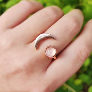 Può includere: Un anello in oro rosa con un design a forma di mezzaluna e una pietra rotonda bianca.