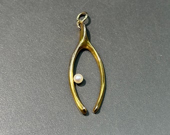 May include: A gold-toned wishbone pendant with a small white pearl in the center.