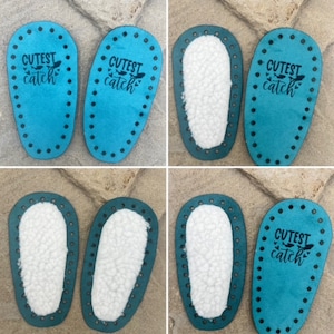 Puede incluir: Un conjunto de suelas de zapato ovaladas de color azul cerceta con agujeros preperforados en los bordes para coser. Algunas suelas tienen un forro de piel sint&eacute;tica blanca, mientras que otras muestran el texto negro Cutest catch.