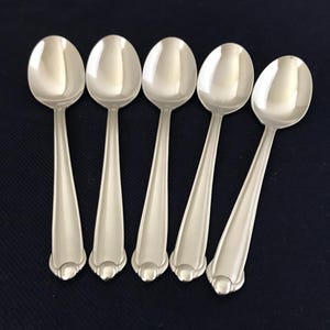 May include: Five silver spoons with rounded bowls and ornate handles.