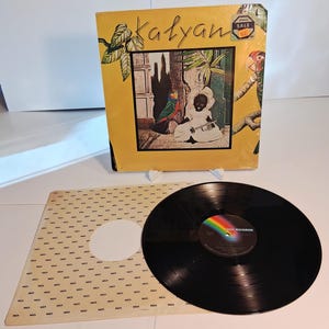 May include: A vintage vinyl record album titled "Kalyan" with a yellow cover featuring an illustration of a person playing an instrument. The album is sealed with a "Special Sale" sticker. The record and its sleeve are visible.