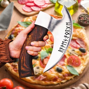 May include: A large, silver pizza cutter with a wooden handle. The blade is curved and has runes inscribed on it. The cutter is being held over a pizza with pepperoni, mushrooms, and other toppings.