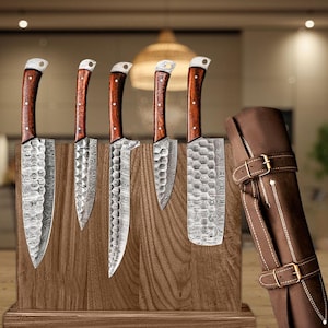 May include: Set of six kitchen knives with wooden handles and a leather knife roll. The knives have a Damascus steel blade pattern.