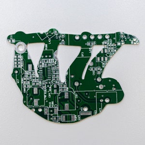 May include: A green circuit board shaped like the letter 'W' with various electronic components and markings, including numbers and letters.