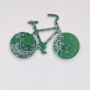 Puede incluir: Un circuito impreso verde con forma de bicicleta. El circuito impreso tiene un dise&ntilde;o detallado con muchos componentes peque&ntilde;os.