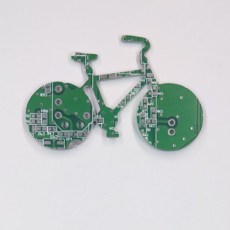 Puede incluir: Un circuito impreso verde con forma de bicicleta. El circuito impreso tiene un dise&ntilde;o detallado con muchos componentes peque&ntilde;os.