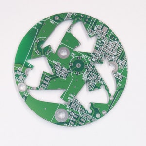 May include: A green circuit board with a three-leaf clover design. The board has a circular shape and is made of copper and green epoxy.