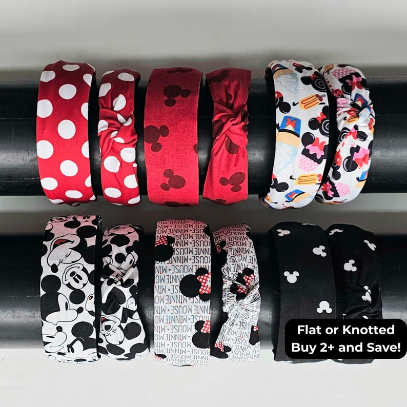 May include: A collection of twelve fabric headbands featuring various patterns including red with white polka dots, red with Mickey Mouse silhouettes, white with character prints, black with Mickey Mouse faces, and black with white Mickey Mouse icons.