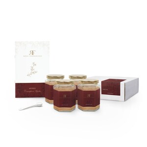 May include: Four glass jars filled with a light brown powder labeled "MYRRH Commiphora Myrrha" with a gold lid and a gold "RF" logo. The jars are on a white surface with a white box and a small white spoon.