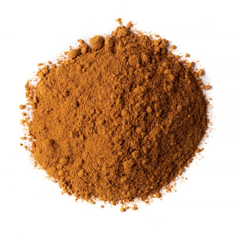 May include: A close-up of a pile of ground cinnamon, a warm brown spice with a sweet and slightly woody aroma.