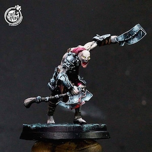May include: A painted miniature figure of a creature with a white body, red eyes, and a red and black loincloth. The creature is holding two axes, one in each hand. The figure is standing on a black base.