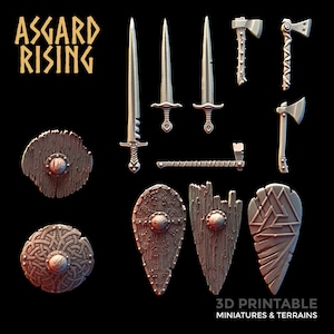 May include: A set of 3D printable miniatures and terrains for tabletop gaming, featuring swords, axes, shields, and other Viking-themed items. The set includes a variety of shield designs, including round, oval, and triangular shapes. The swords and axes are detailed and realistic, with sharp edges and intricate designs. The text "ASSGARD RISING" is visible in the top left corner of the image.
