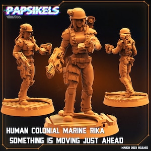 May include: A 3D printed miniature of a female human colonial marine soldier holding a rifle. The miniature is painted in a light brown color and is standing on a circular base. The text "HUMAN COLONIAL MARINE RIKA SOMETHING IS MOVING JUST AHEAD" is printed below the miniature.