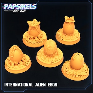 May include: Five miniature alien egg sculptures on circular bases. Each egg is a different color and has a unique texture. The bases are all a light brown color and have a textured surface. The text "INTERNATIONAL ALIEN EGGS" is printed in black at the bottom of the image.