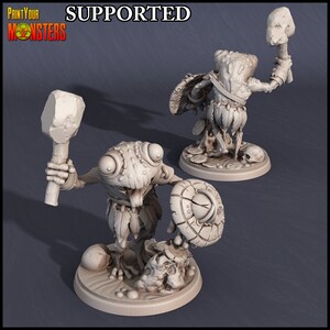 Puede incluir: Una miniatura impresa en 3D de una criatura parecida a una rana que sostiene un garrote y un escudo. La miniatura está pintada de color gris claro y está de pie sobre una base redonda. La miniatura forma parte de un conjunto de miniaturas de fantasía para juegos de rol de mesa.