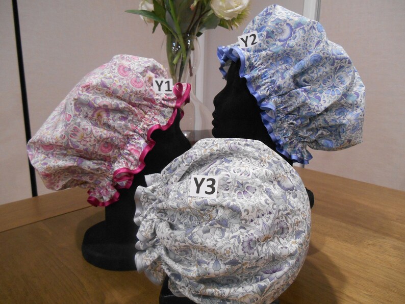 K&ouml;nnte beinhalten: Drei Duschhauben mit Blumenmustern. Die Hauben werden auf Mannequins pr&auml;sentiert. Die Hauben sind mit Y1, Y2 und Y3 beschriftet.