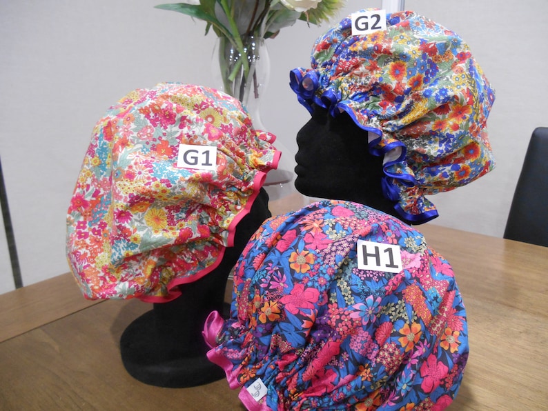 Pu&ograve; includere: Tre cuffie da doccia floreali con bordi rosa, blu e bianchi. Le cuffie sono etichettate G1, G2 e H1.