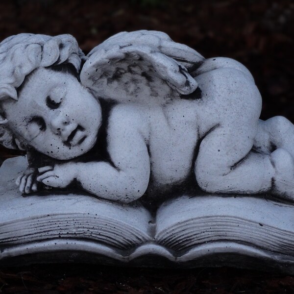 Schlafende Baby-Engelfigur. Beton-Engel auf Buch. Gartendekoration. Erinnerungsornament zum Verlust des Babys