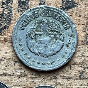 May include: A silver coin with the words "VEINTE CENTAVOS" around the edge. The coin features a stylized eagle with a shield in its talons.