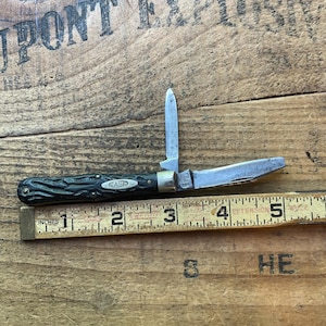 May include: A vintage Case pocket knife with two blades extended. The handle is dark green with a textured pattern and the Case logo. The knife is next to a ruler, measuring approximately 5 inches in length.