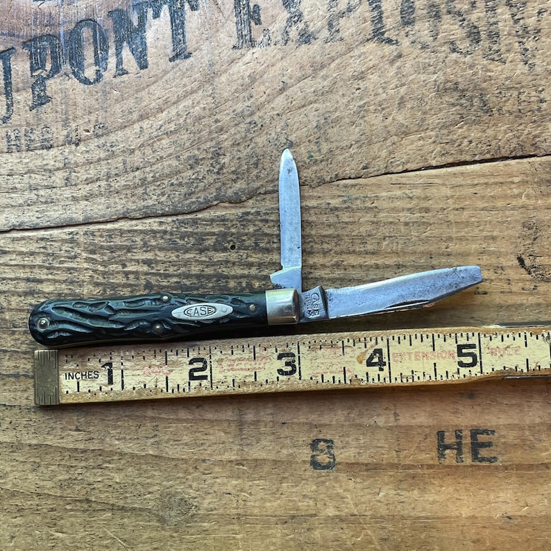May include: A vintage Case pocket knife with two blades extended. The handle is dark green with a textured pattern and the Case logo. The knife is next to a ruler, measuring approximately 5 inches in length.