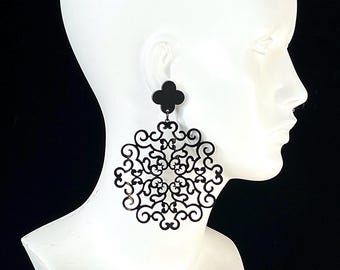 May include: Black statement earrings with a floral design. The earrings are attached to a black four-leaf clover stud. The large, openwork design is a bold accessory.