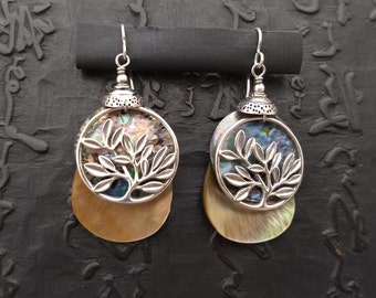 Sterling leafy branch (openwork) over a round disc of paua shell and a teardrop shaped mother of pearl dangle, topped by a sterling cap.