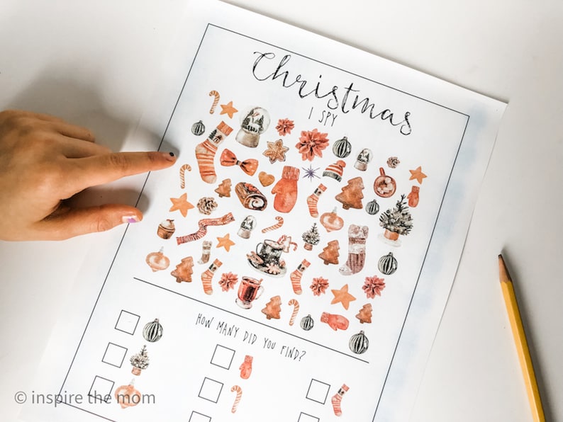 May include: A printable Christmas I Spy game with a white background and illustrations of various Christmas items in shades of brown, orange, and red. The items include ornaments, candy canes, mittens, stockings, and Christmas trees. The text "Christmas I Spy" is written in black cursive at the top of the page. Below the illustrations is a section with boxes for counting how many of each item you can find.