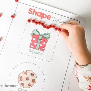 May include: A worksheet with the words "Shape Outline" in red. A hand is placing red beads around a square-shaped gift box illustration. The word "square" is below the gift box. A cookie illustration is below the gift box.