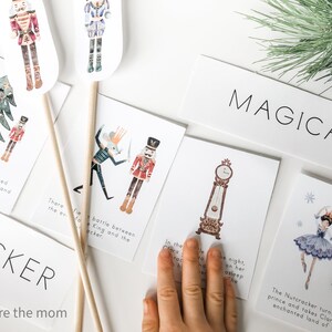 Op de afbeelding: Een set met printbare kaarten met illustraties van personages uit het ballet De Notenkraker. De kaarten bevatten een notenkraker-soldaat, een muizenkoning, een klok en een ballerina. De kaarten zijn gedrukt op wit karton en hebben een aquarel-achtige stijl. De tekst op de kaarten luidt "Magisch" en "De Notenkraker verandert in een prins en neemt Clara mee naar een betoverd land van sneeuw."