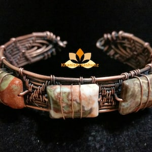 May include: A copper wire wrapped bracelet with three rectangular brown and white patterned stones. The bracelet is woven with a copper wire design.