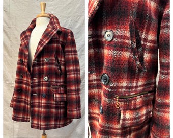 May include: A red, black, and white plaid wool coat with a double-breasted design. The coat features black buttons, a notched collar, and a zippered pocket. The coat is displayed on a mannequin.