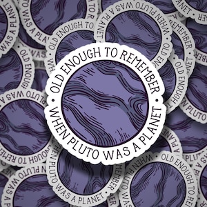 May include: A sticker with a purple and white design. The sticker says "Old enough to remember when Pluto was a planet."