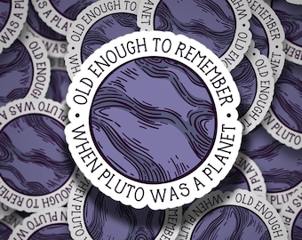 Op de afbeelding: Een sticker met een paars en wit ontwerp. De sticker zegt "Oud genoeg om te herinneren toen Pluto een planeet was."