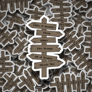 May include: A brown wooden signpost with six directional arrows pointing to different locations. The signpost is labeled with the following locations: Cliffs of Insanity, Florin, Gilder, Fire Swamp, Pit of Despair, and Miracle Max.
