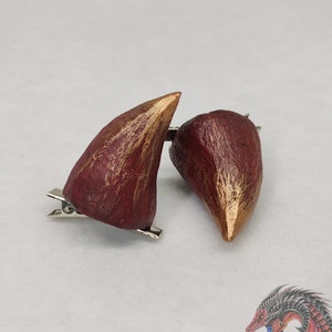 May include: A pair of red and gold horn hair clips. The horns are made of polymer clay and have a textured finish. The clips are silver metal.
