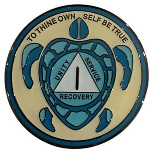 Peut inclure: Une épingle ronde en émail bleu et blanc avec un motif de tortue. La tortue tient un triangle blanc avec les mots "Unité", "Service" et "Rétablissement" dessus. Les mots "To Thine Own Self Be True" sont écrits autour de l'extérieur de l'épingle.