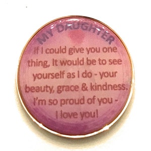 May include: A pink and white round charm with a gold rim. The charm has the text "MY DAUGHTER" at the top and the text "If I could give you one thing, It would be to see yourself as I do - your beauty, grace & kindness. I'm so proud of you - I love you!" in the center.