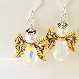 May include: A pair of silver dangle earrings featuring a gold angel with a pearl and iridescent crystal accents.