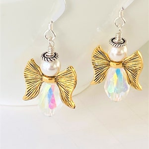 May include: Gold angel dangle earrings with iridescent crystal and white pearl accents.