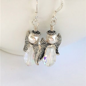 May include: Silver angel dangle earrings with a white pearl and clear crystal bead.