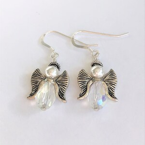 May include: A pair of silver angel dangle earrings with clear crystal beads. The angels have silver wings and a pearl head.