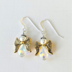 May include: A pair of silver dangle earrings with gold angel charms and iridescent crystal beads.