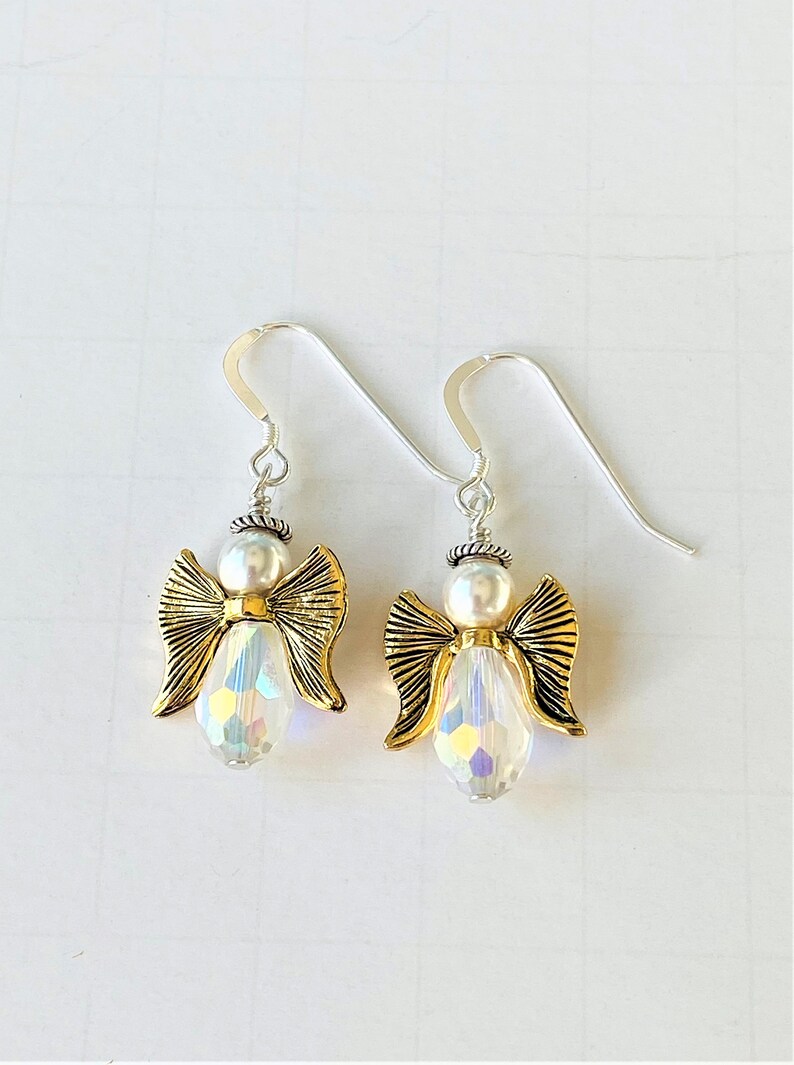 May include: A pair of silver dangle earrings with gold angel charms and iridescent crystal beads.