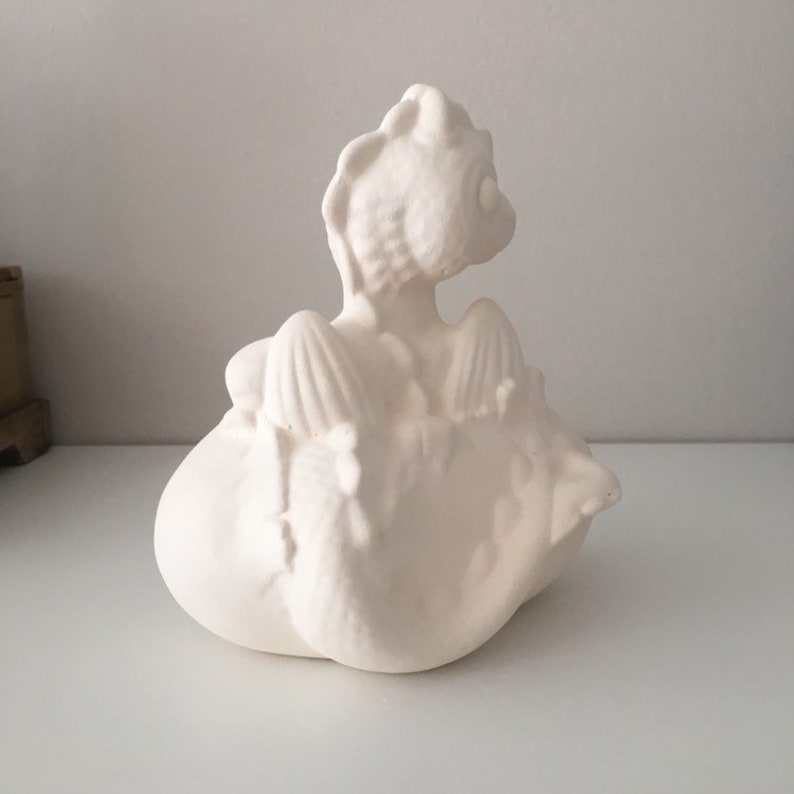 May include: White ceramic dragon figurine with wings outstretched, perched on a cloud-shaped base.