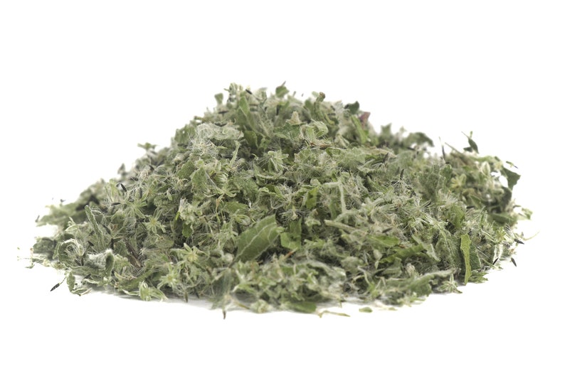 May include: A pile of dried, green, and brown herbs. The herbs are finely chopped and have a slightly fuzzy texture.
