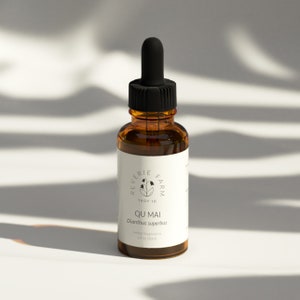 May include: A brown glass bottle with a black dropper top and a white label. The label says "Reverie Farm Troy ID Qu Mai Dianthus superbus Herbal Supplement 1 fl oz (30ml)"